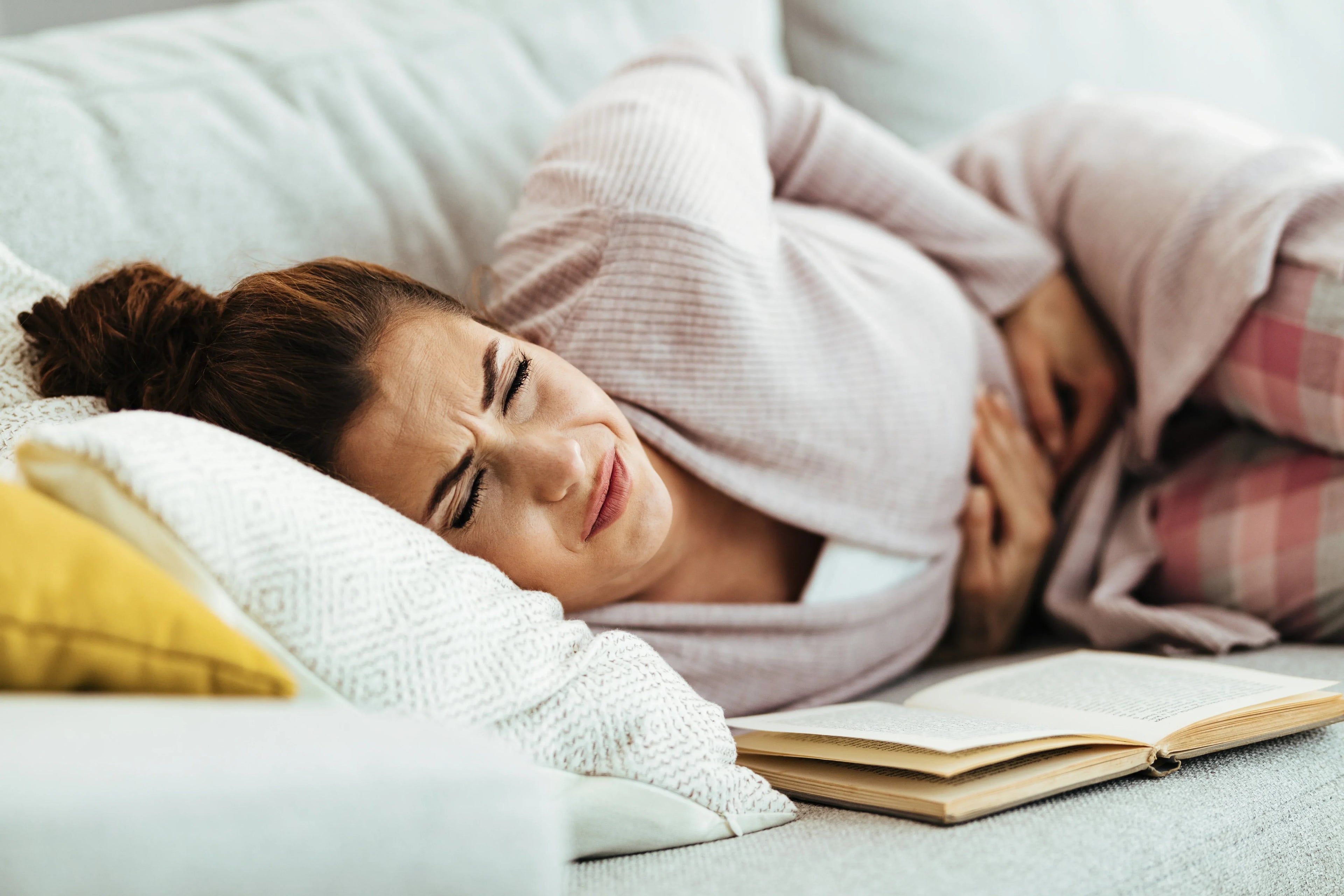 young woman lying down feeling pain in her abdomen